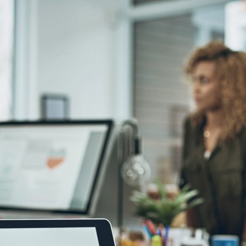 Closeup shot of a laptop with graphs on the screen and a team working in the background